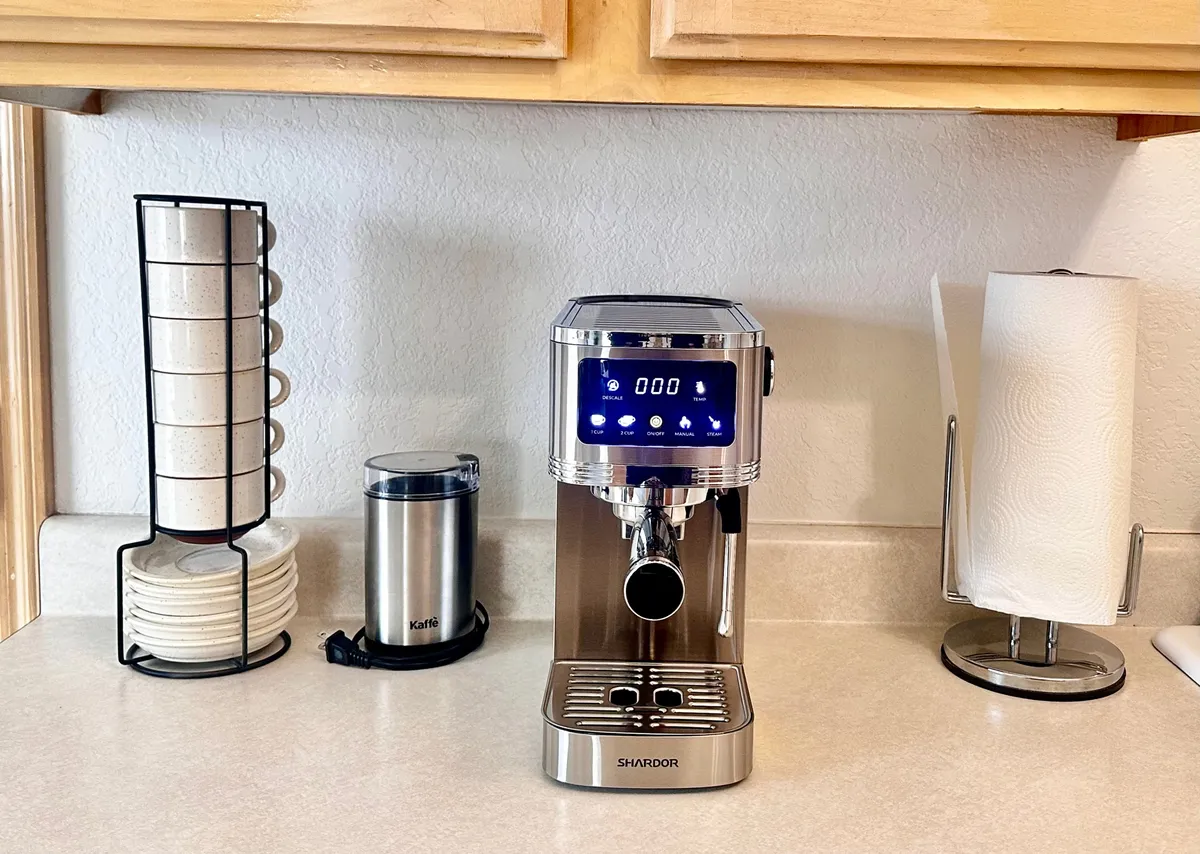 A cozy kitchen setup highlighting a modern coffee machine, a stack of saucers, and a coffee grinder, inviting guests to brew and enjoy their morning beverage together. The ambiance is both functional and inviting, suggesting a perfect start to a day of exploration or relaxed mornings before heading out.