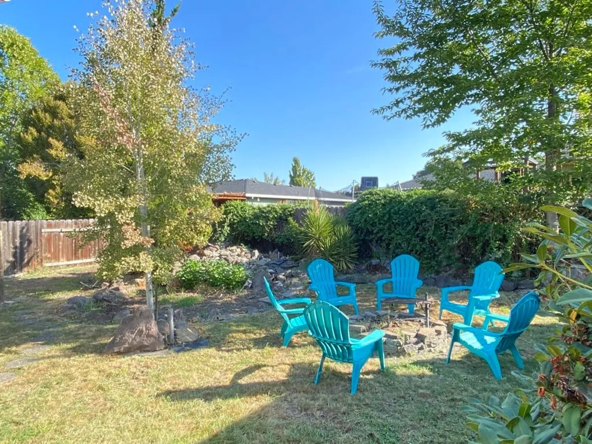 An outdoor seating area featuring turquoise chairs surrounding a cozy fire pit, all nestled among lush greenery. The arrangement sets the stage for relaxed evenings, stargazing, and socializing after a day of local adventures.