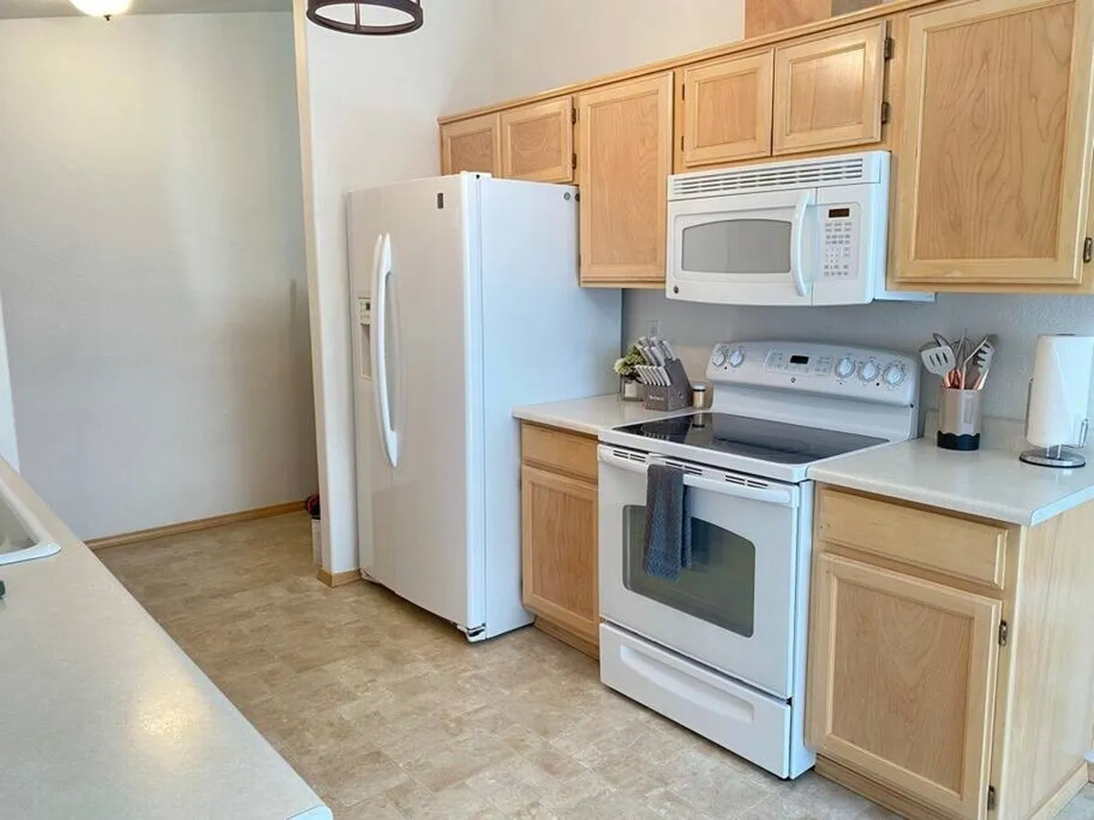 A classic kitchen scene with white appliances, wooden cabinets, and generous countertop space. The setup is ideal for meal prep, baking, and bringing the entire family together for shared kitchen activities.