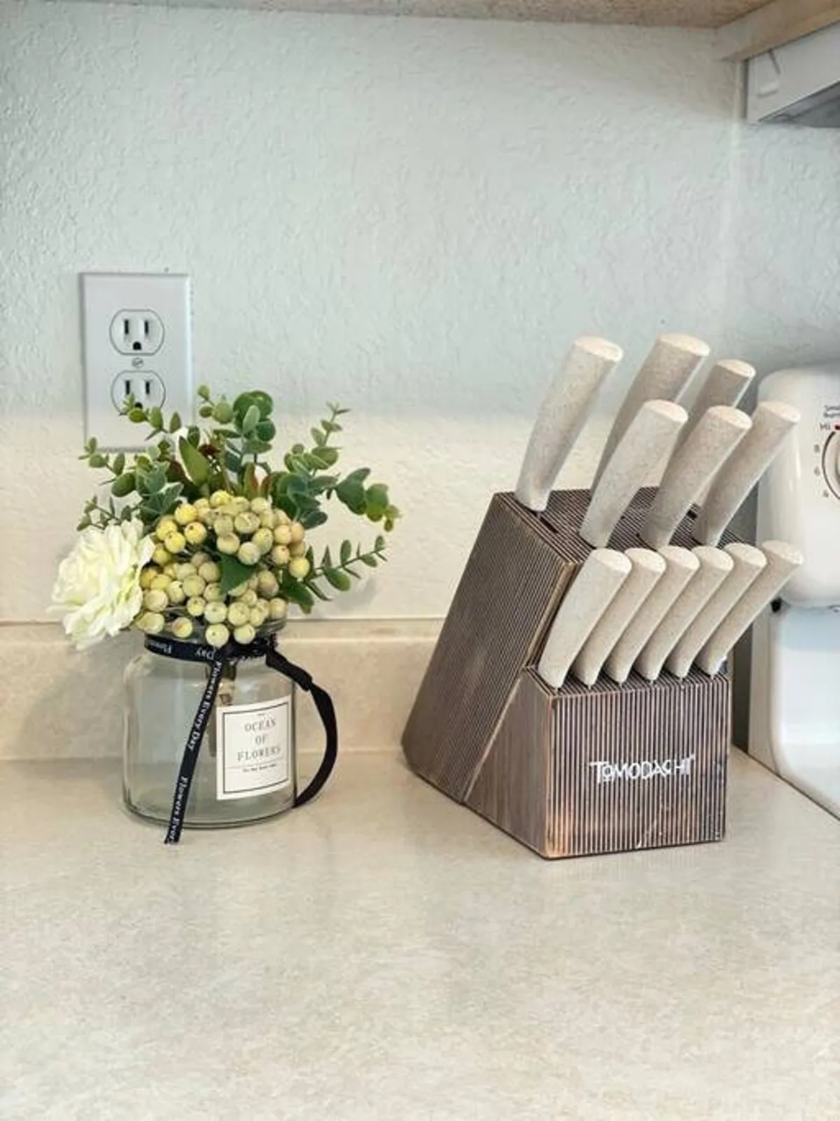 Focused on a fresh flower arrangement and a knife block on the counter, this image captures the lively, welcoming spirit of meal preparation and the attention to detail in the kitchen’s design. The scene hints at festive occasions and engaging conversations around food.